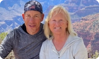David and his wife sitting together with a scenic canyon in the background.